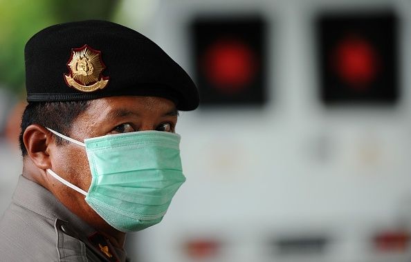 Un officier de la police indonésienne porte un masque comme il garde la procédure d'identification de vol AirAsia QZ8501 catastrophe Un officier de la police indonésienne porte un masque comme il garde la procédure d'identification de vol AirAsia QZ8501 catastrophe