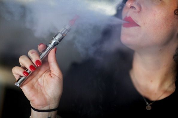 Une femme à l'aide d'une e-cigarette, souffler la vapeur qui contient de la nicotine.