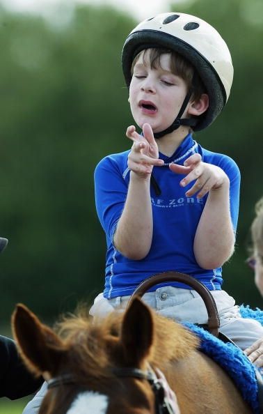 Un garçon autiste hausse un cheval.